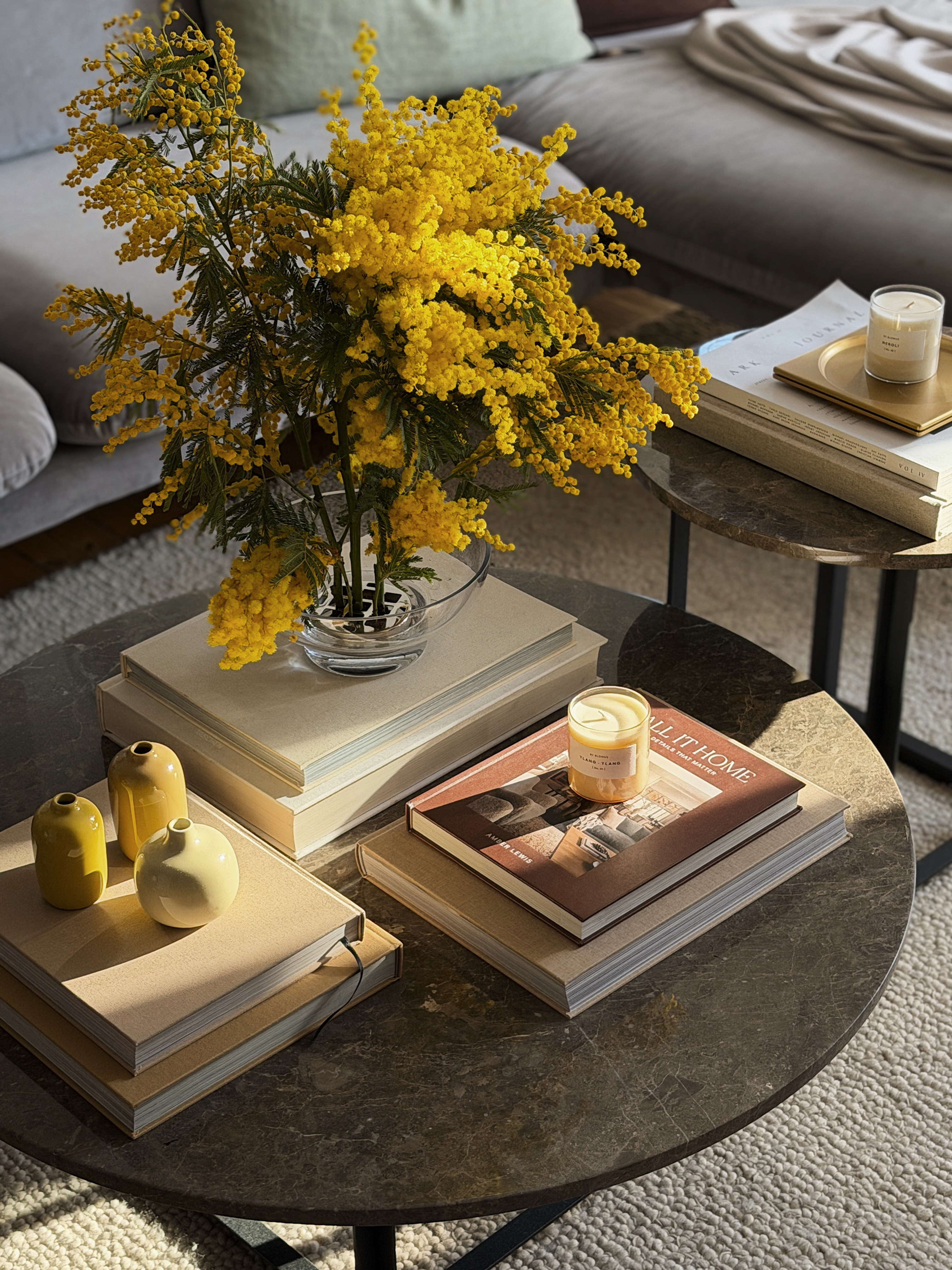 Wohnzimmer-Couchtisch mit gelben Mimosen in Vase, Büchern und blomus Vasen als Dekoration